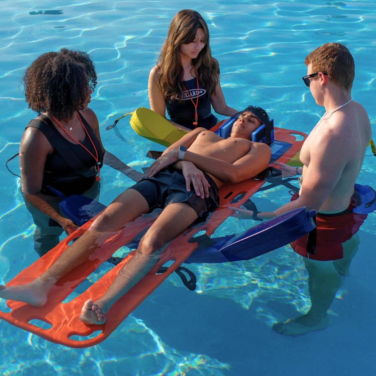 Kiefer rescue board with a person secured and lifeguards assisting in a pool.