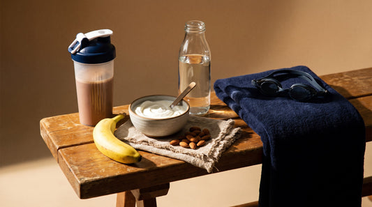 Post-practice nutrition on a bench with a recovery shaker, fruit, yogurt, nuts and water