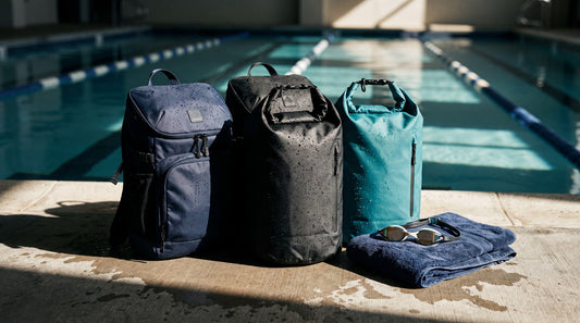 Waterproof swim backpacks and roll-top dry bags on a wet pool deck