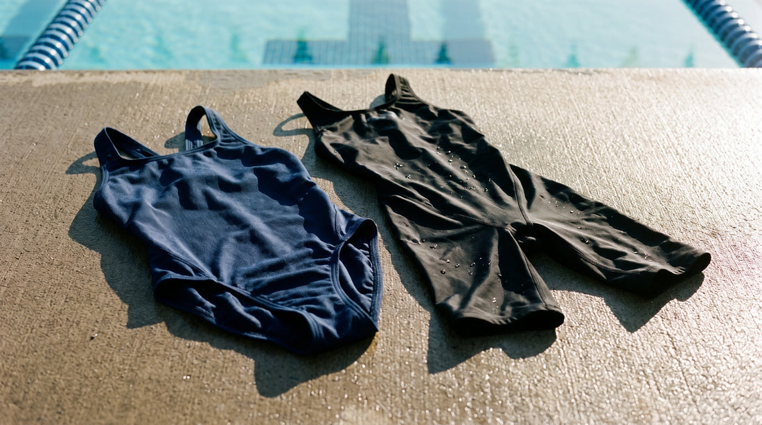 A polyester training swimsuit laid beside a knee-length racing tech suit on a pool deck