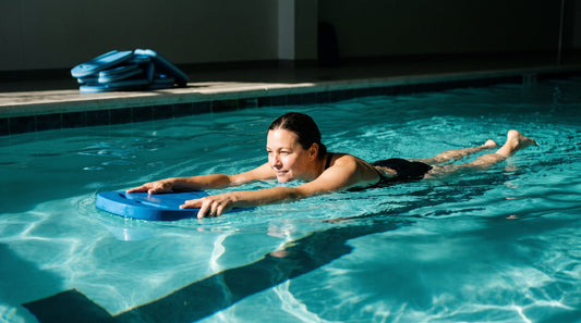 Beginner swimmer kicking down a lane holding a foam kickboard