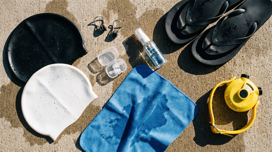 Swim accessories flat lay with caps, nose clips, ear plugs, anti-fog spray and a tempo trainer