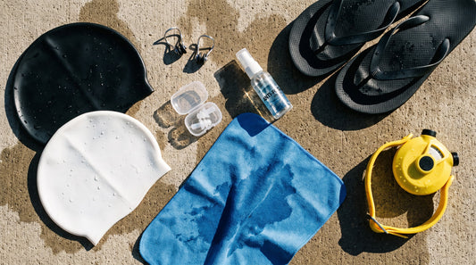 Swim accessories flat lay with caps, nose clips, ear plugs, anti-fog spray and a tempo trainer
