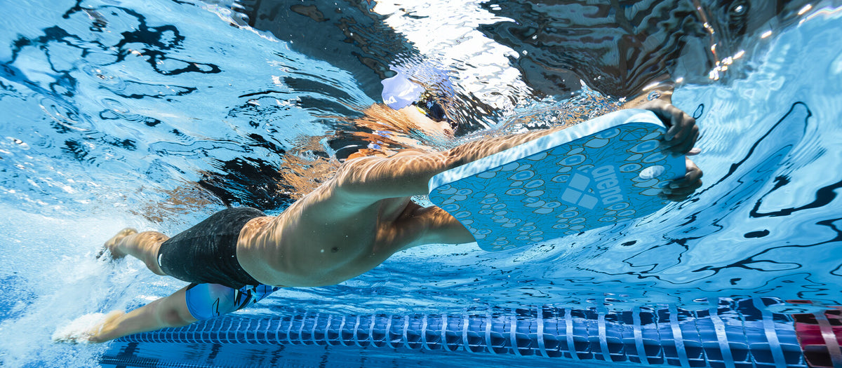 Swimmer kicking underwater holding an arena kickboard