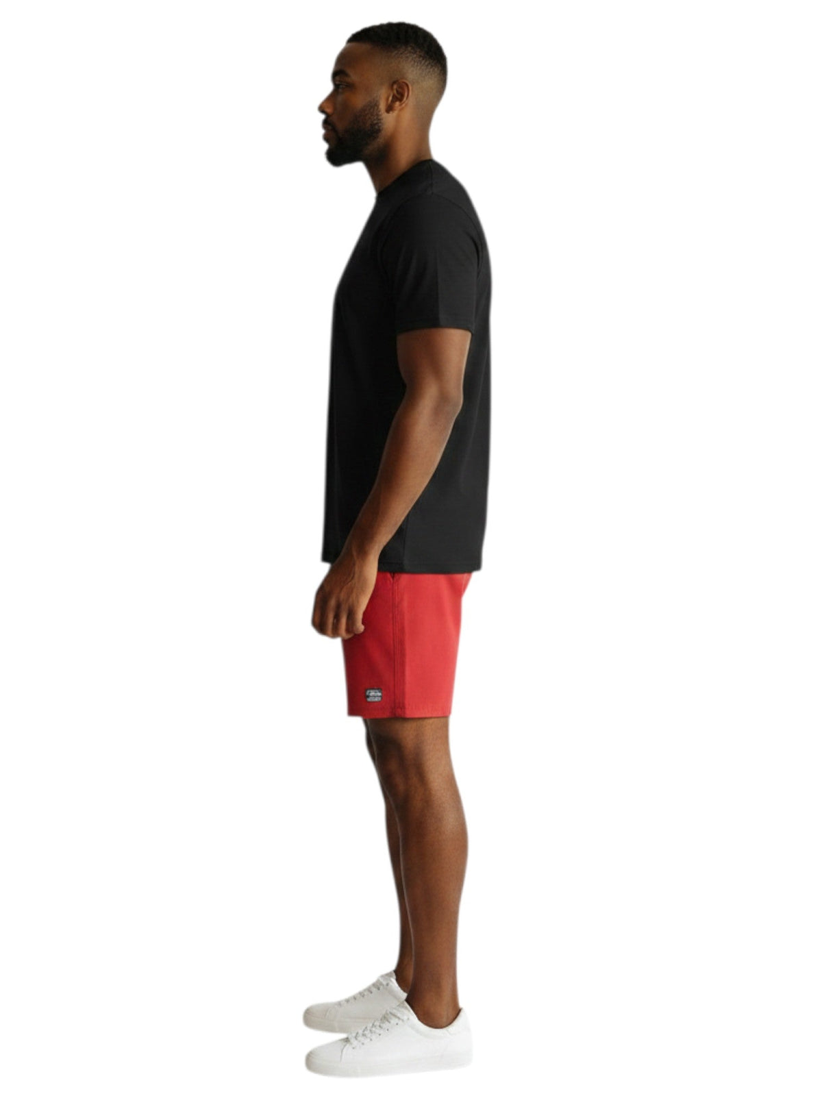 A man wearing a black Kiefer short sleeve crew neck rashguard and red shorts, side profile view.