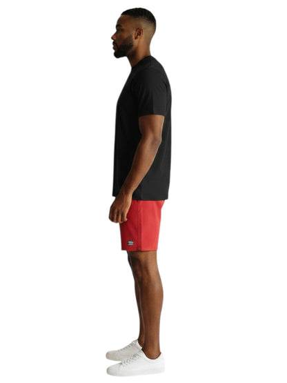 A man wearing a black Kiefer short sleeve crew neck rashguard and red shorts, side profile view.