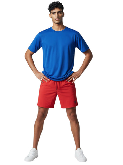 Male model wearing Kiefer blue short sleeve crew neck rashguard with red shorts and white sneakers.
