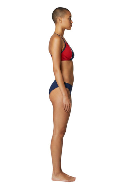 Model wearing Kiefer RISE Guard red and navy blue splice bikini with flat-locked seams, side view